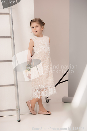 Image of Little pretty girl with flowers dressed in wedding dresses