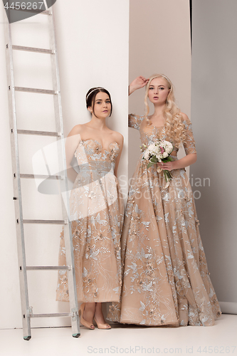 Image of Brides in beautiful dress standing indoors in white studio interior like at home. Trendy wedding style shot. Young attractive caucasian model like a bride tender looking.