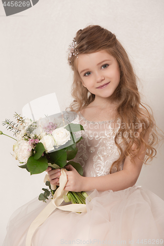 Image of Little pretty girl with flowers dressed in wedding dresses