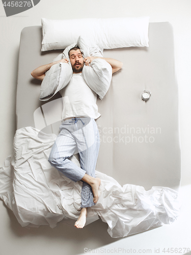 Image of Top view photo of young man sleeping in a big white bed