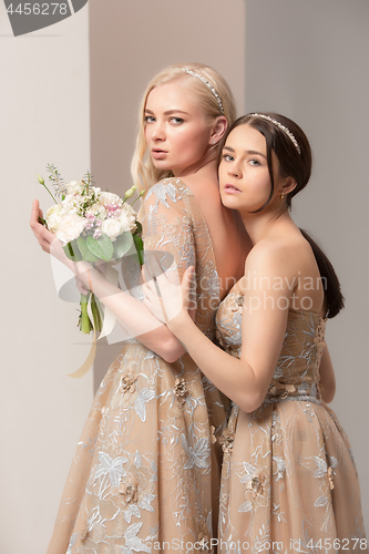 Image of Brides in beautiful dress standing indoors in white studio interior like at home. Trendy wedding style shot. Young attractive caucasian model like a bride tender looking.