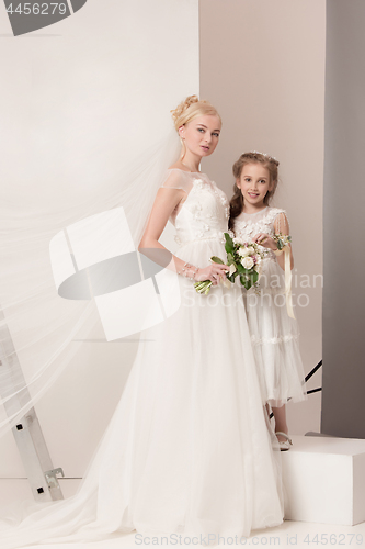 Image of Little pretty girls with flowers dressed in wedding dresses