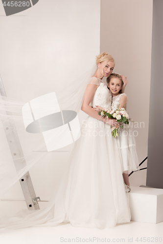 Image of Little pretty girls with flowers dressed in wedding dresses