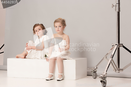 Image of Little pretty girls with flowers dressed in wedding dresses