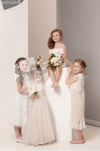 Image of Little pretty girls with flowers dressed in wedding dresses