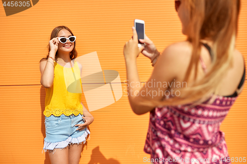 Image of teenage girl photographing friend by smartphone