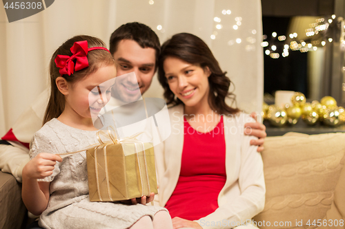 Image of happy family with christmas present at home