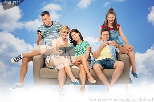 Image of friends with tablet pc and smartphones sit on sofa