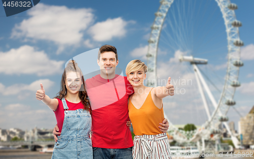 Image of happy friends showing thumbs up over ferry wheel