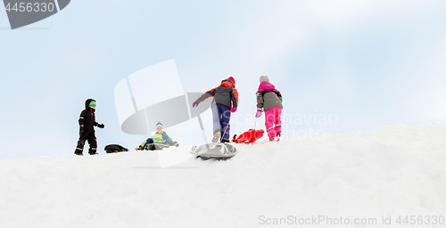 Image of kids with sleds climbing snow hill in winter