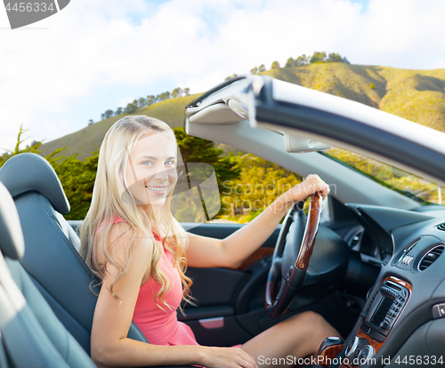 Image of happy woman driving convertible car at big sur 