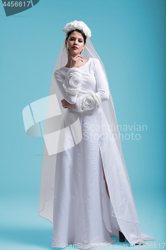 Image of beautiful woman wearing wedding dress against cyan background