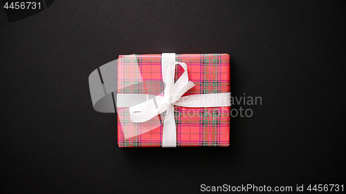 Image of Red gift box with white bow on black table, top view