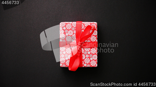 Image of Red gift box with red bow on black table, top view