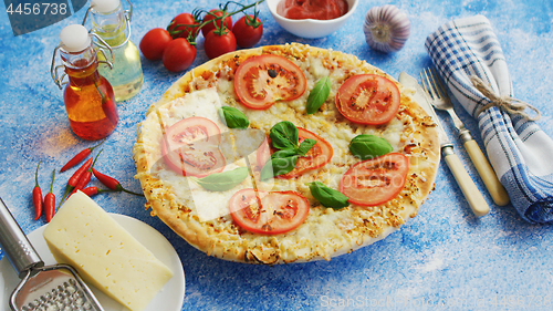 Image of Delicious italian pizza served on blue stone table, shot from side