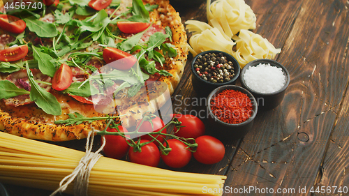 Image of Italian food background with pizza, raw pasta and vegetables on wooden table