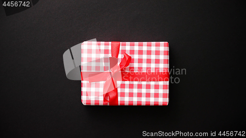 Image of Red gift box with red bow on black table, top view