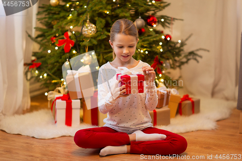 Image of smiling girl with christmas gift at home