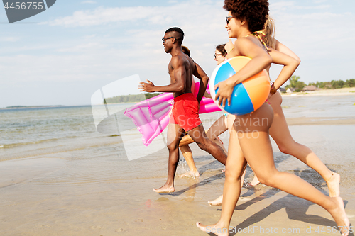 Image of friends run with beach ball and swimming mattress