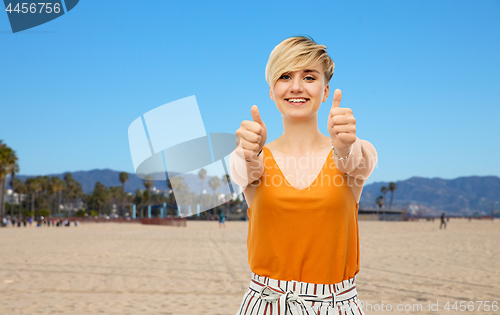 Image of happy smiling young woman showing thumbs up