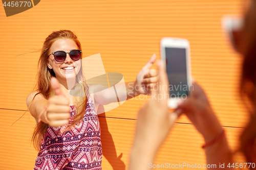 Image of teenage girl photographing friend by smartphone