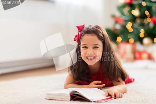 Image of happy girl reading book at home on christmas