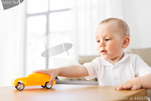 Image of baby boy playing with toy car at home