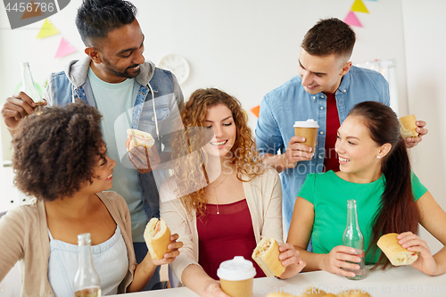 Image of happy friends or team eating at office party