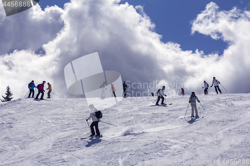 Image of Skiers on mountainside  in the background light