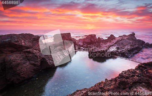 Image of Blazing red sunrise over rock pool