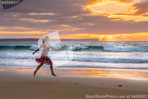 Image of Female running along the beach in wet sand