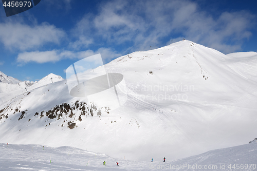 Image of Skiers and snowboarders downhill on trace and mountains with clo