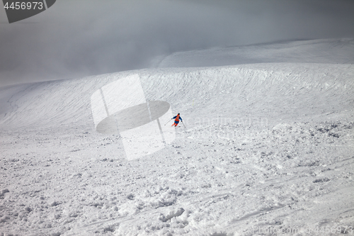 Image of Skier downhill on freeride slope and overcast misty sky before b