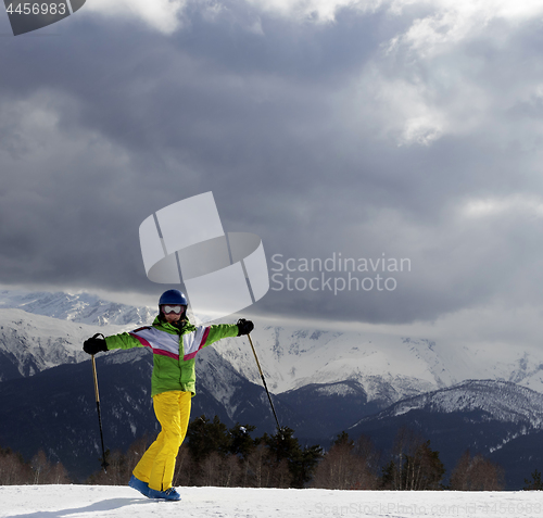 Image of Happy young skier with ski poles in sun mountains and cloudy gra