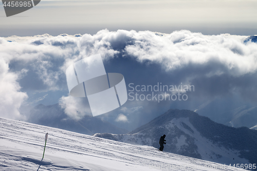 Image of Skier downhill on ski slope and sunlight storm clouds