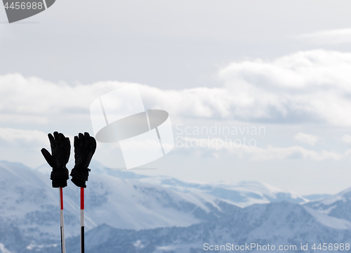 Image of Black gloves on ski poles and snow winter mountains