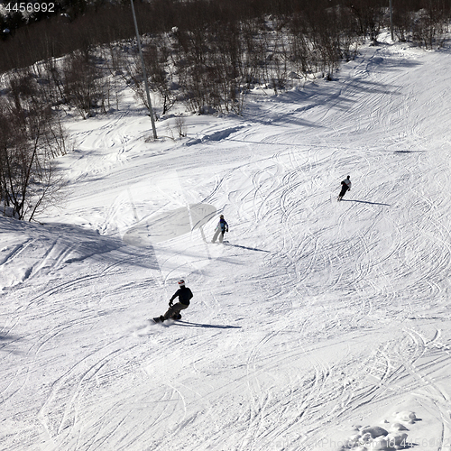 Image of Skier and snowboarders on ski slope at sun winter day