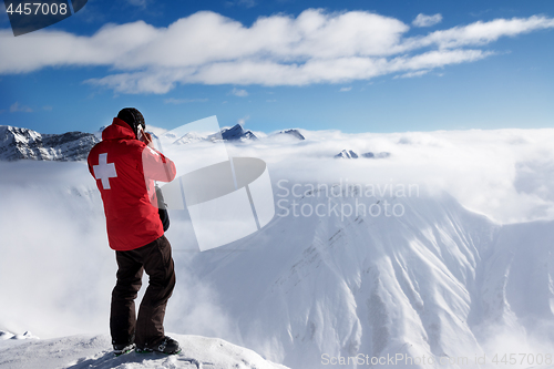 Image of Rescuer at top of mount and snow mountains in fog