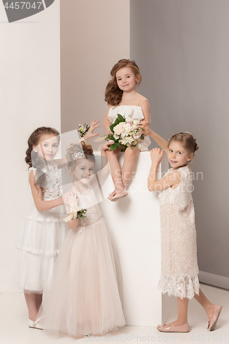 Image of Little pretty girls with flowers dressed in wedding dresses