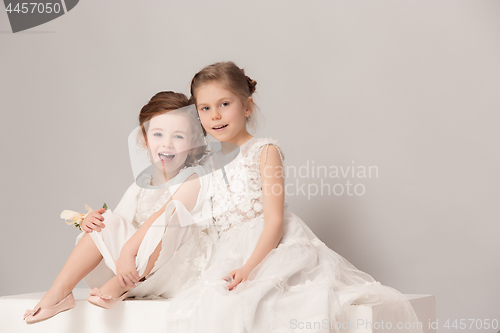 Image of Little pretty girls with flowers dressed in wedding dresses