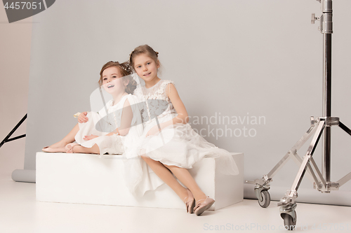 Image of Little pretty girls with flowers dressed in wedding dresses