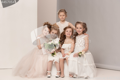 Image of Little pretty girls with flowers dressed in wedding dresses