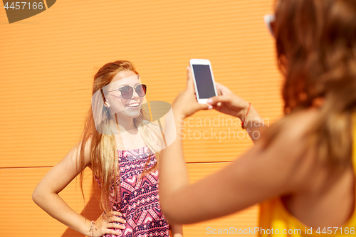 Image of teenage girl photographing friend by smartphone