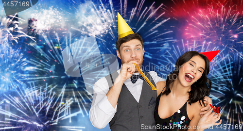 Image of happy couple with party blowers having fun