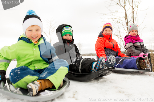 Image of happy little kids sliding on sleds in winter