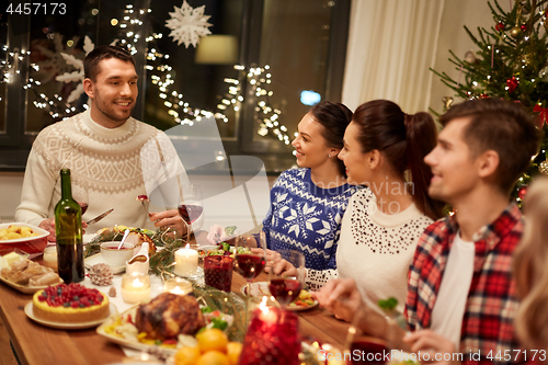 Image of happy friends having christmas dinner at home