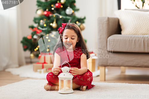 Image of little girl with lantern at home on christmas