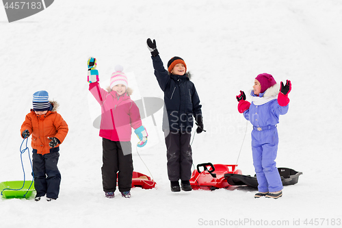 Image of happy kids with sleds waving hands in winter