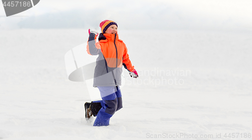 Image of happy girl playing and throwing snowball in winter