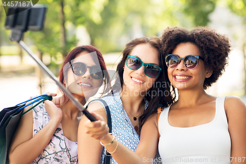 Image of women with shopping bags taking selfie outdoors